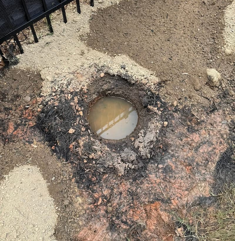 Direct overhead view of standing water trapped in a clay soil percolation test hole