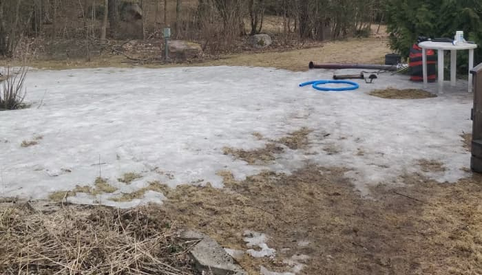 A dense, impermeable sheet of ice covering a residential lawn, illustrating the "ice coffin" effect that suffocates turfgrass by trapping toxic gases.