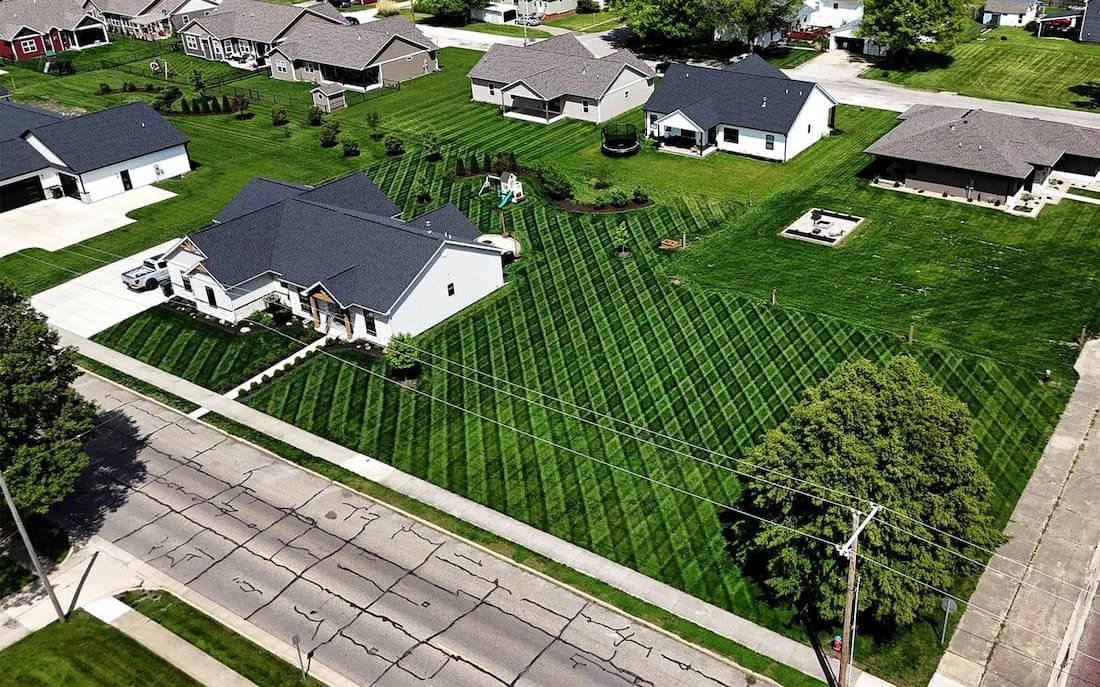Aerial view of a residential neighborhood with several healthy, professionally striped green lawns